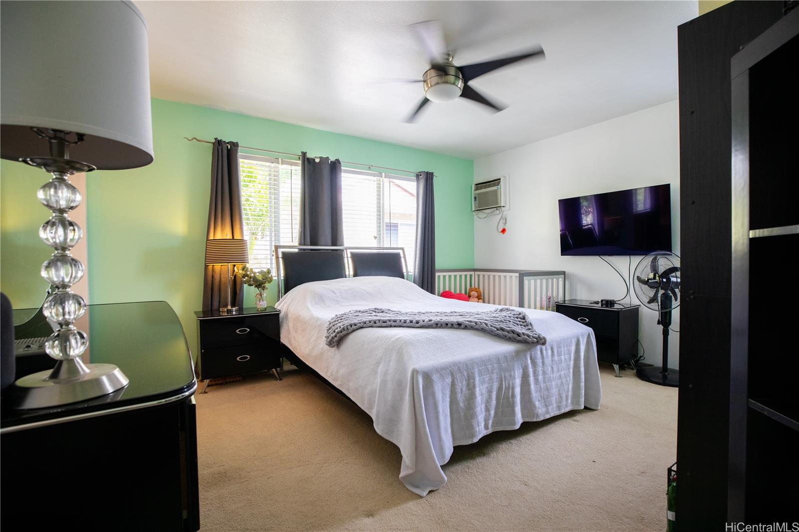 a bedroom with a bed and a flat tv screen on dresser