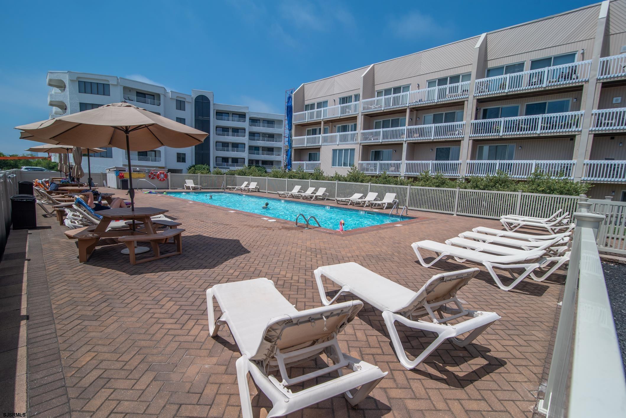 a view of a swimming pool with a table and chairs under an umbrella