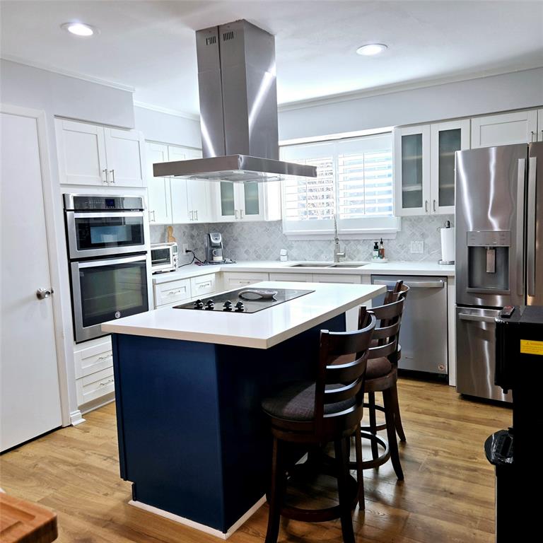 a kitchen with stainless steel appliances a sink a stove a refrigerator cabinets and dining table