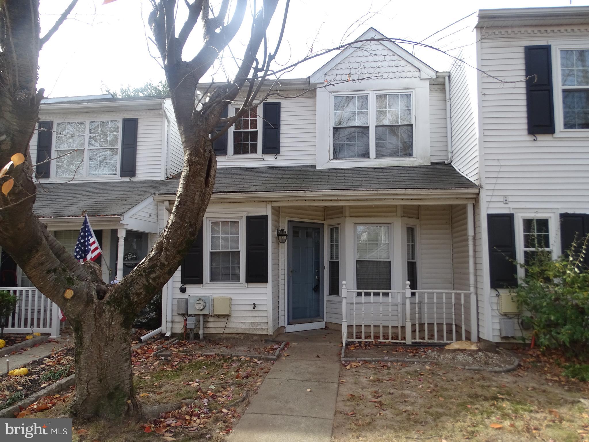 a front view of a house with a large tree