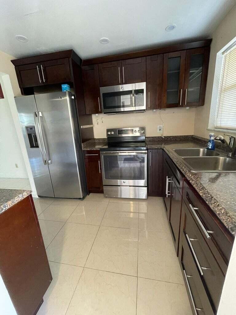 a kitchen with stainless steel appliances granite countertop a sink stove microwave and refrigerator