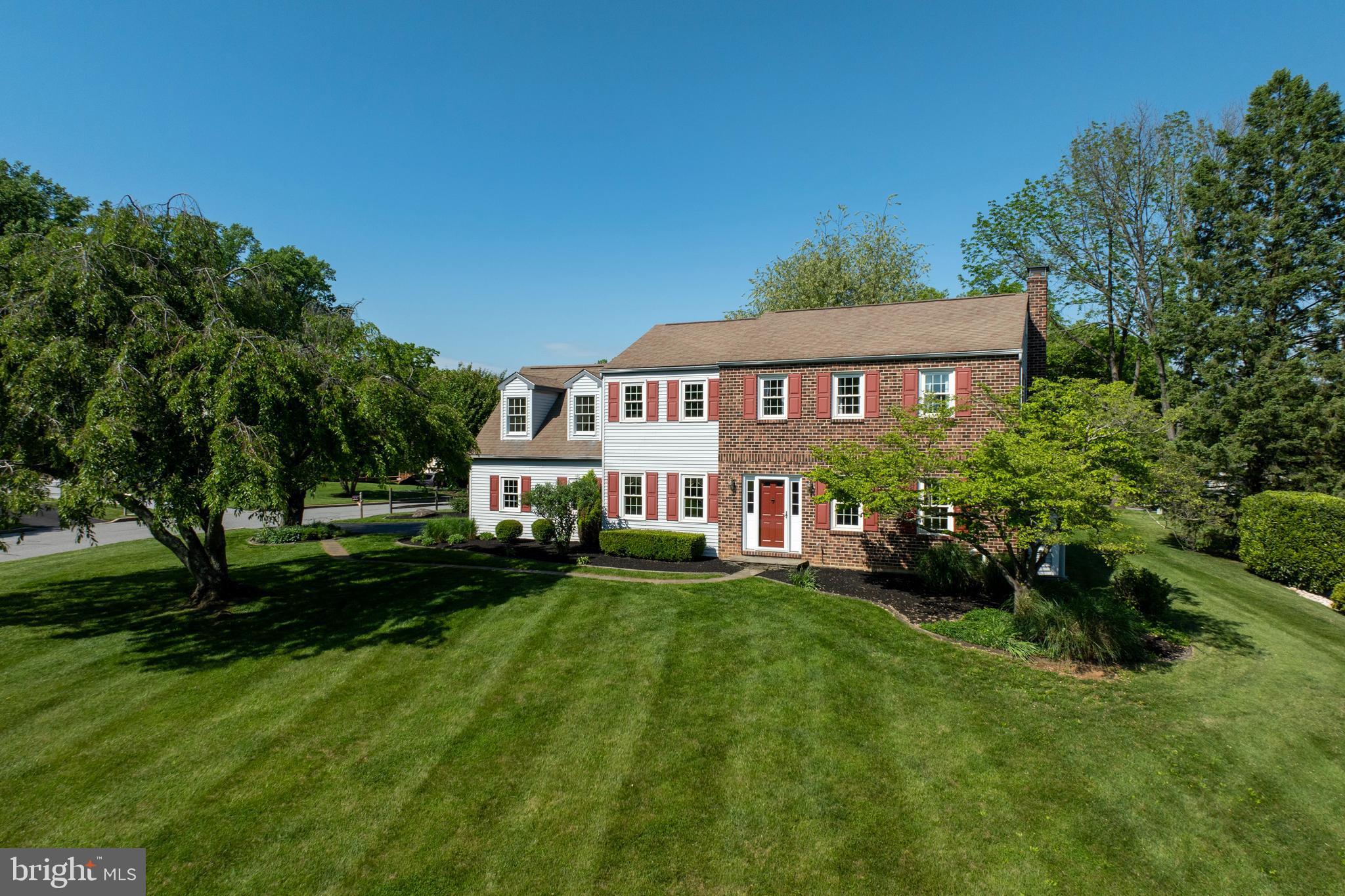 a view of a house with a big yard plants and large trees