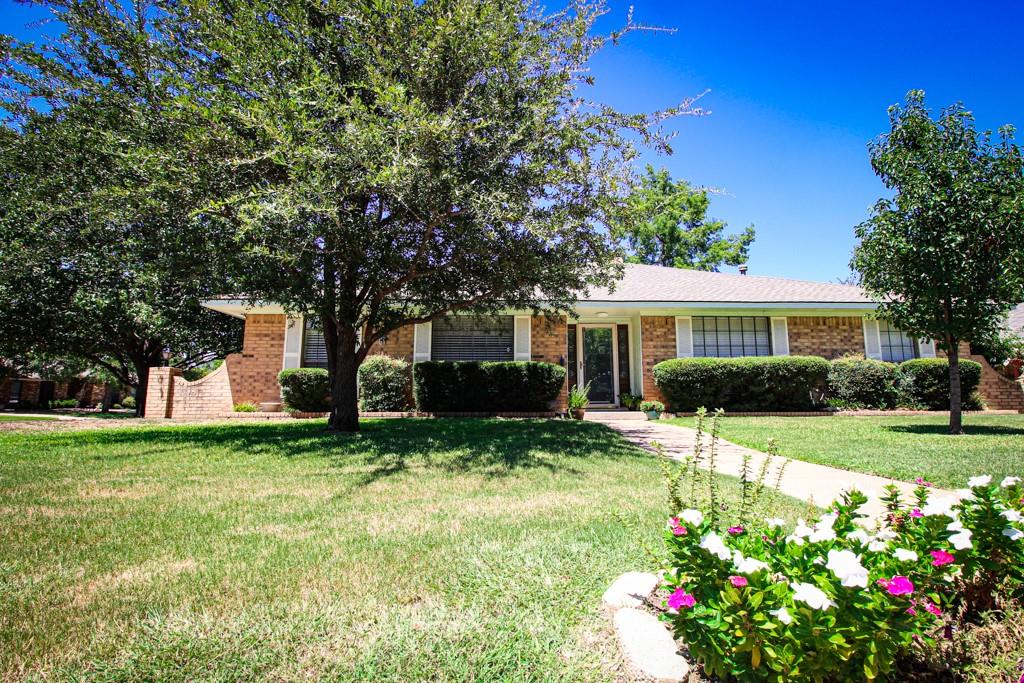 a front view of a house with a yard and trees