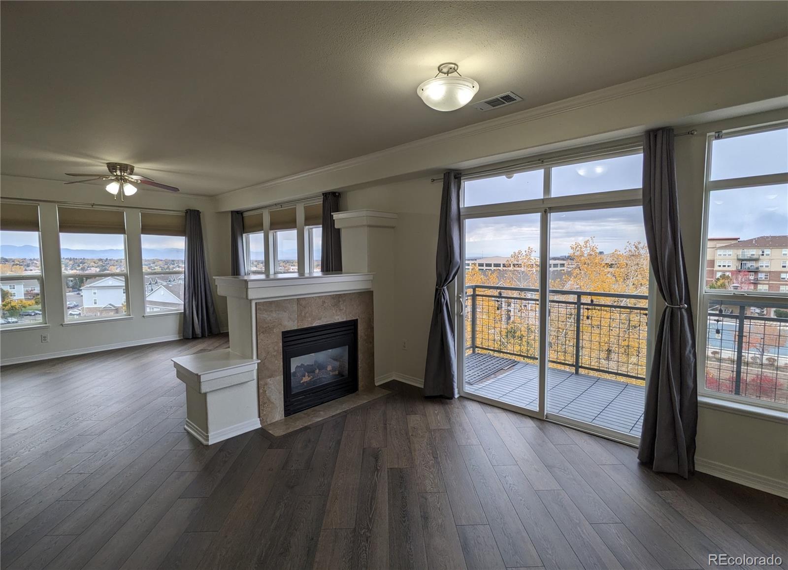 a view of an empty room with wooden floor and a fireplace