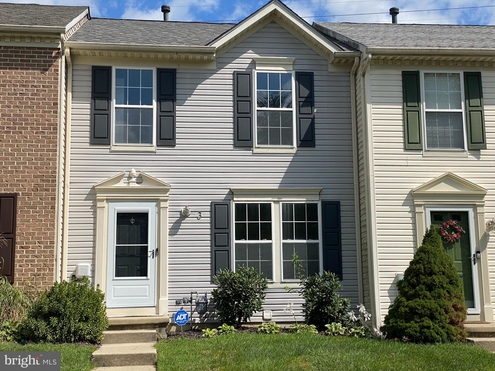 a front view of a house with a yard and potted plants