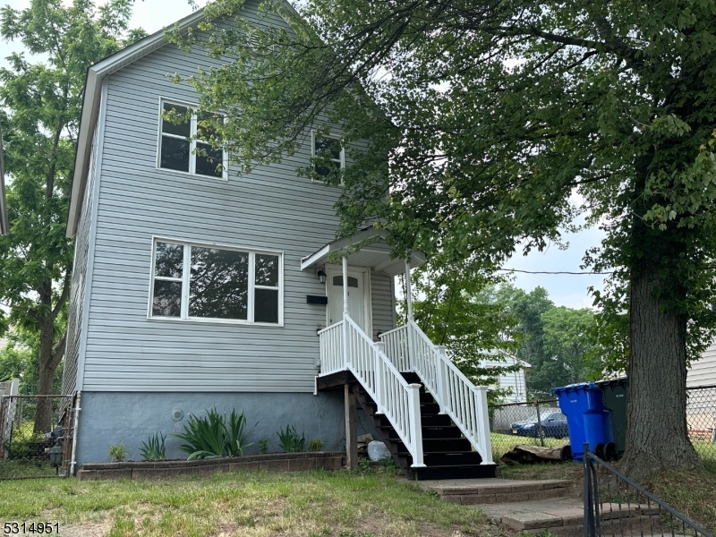 a view of a house with a yard and a large tree