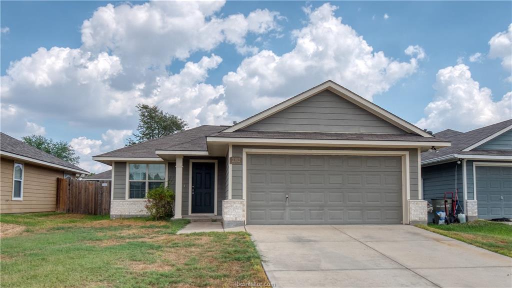 View of front of home with a front yard and a gara