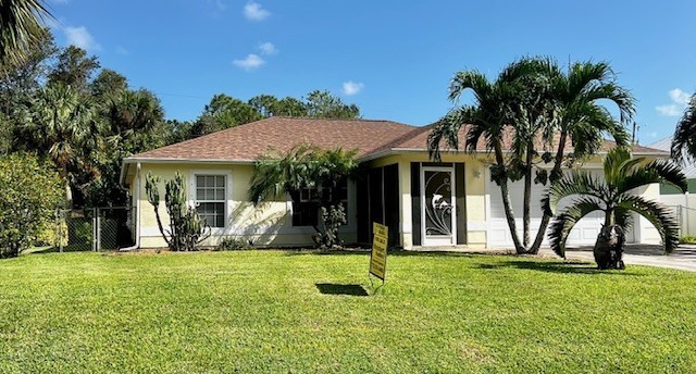 a view of a house with a yard and palm trees