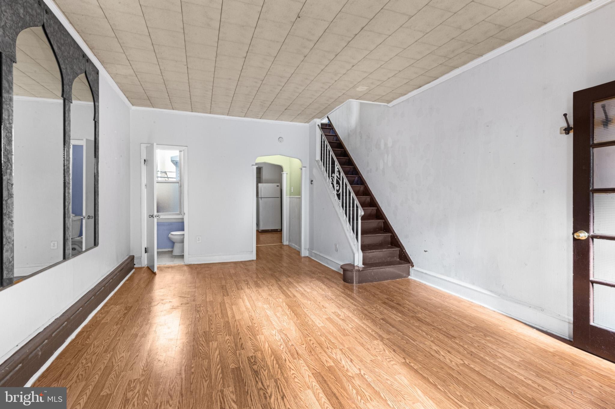 a view of an empty room with wooden floor and stairs