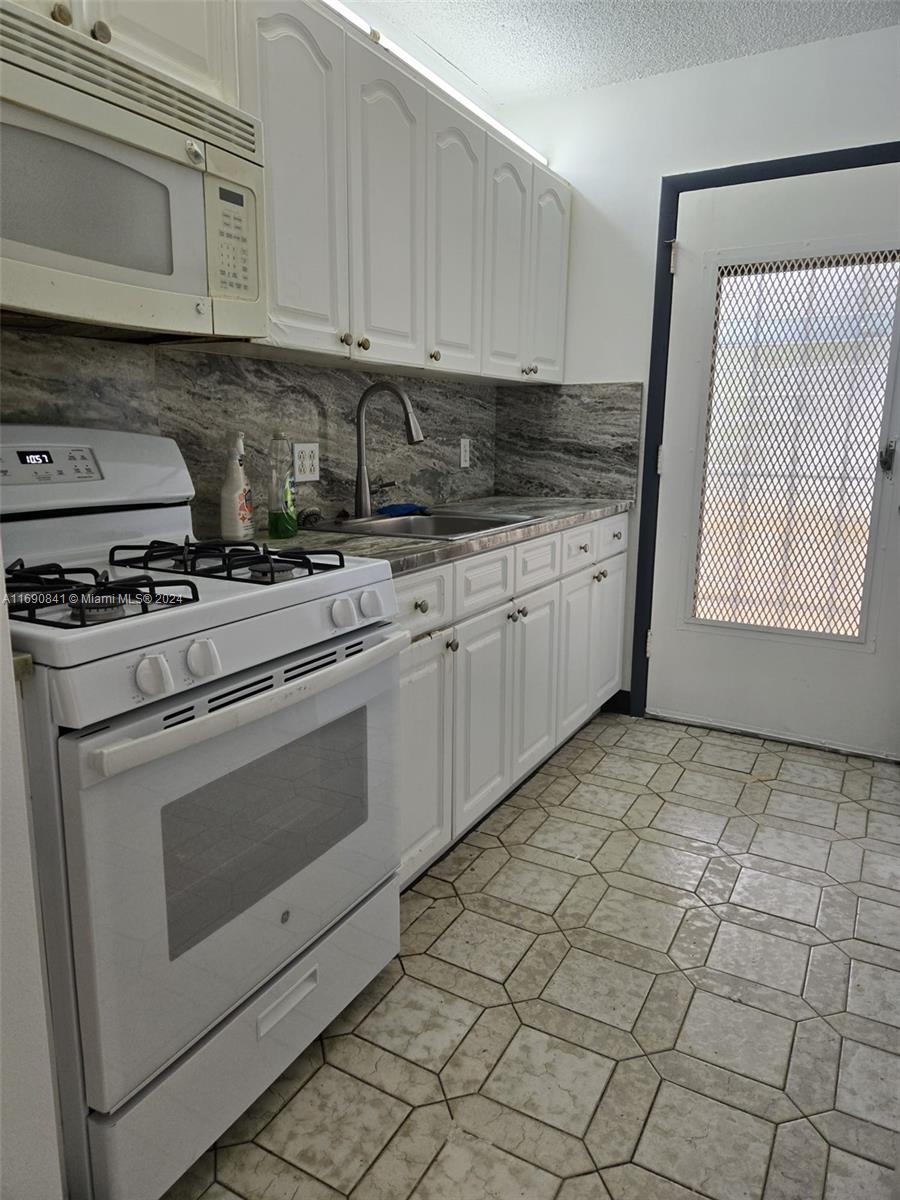 a kitchen with granite countertop white cabinets and white appliances