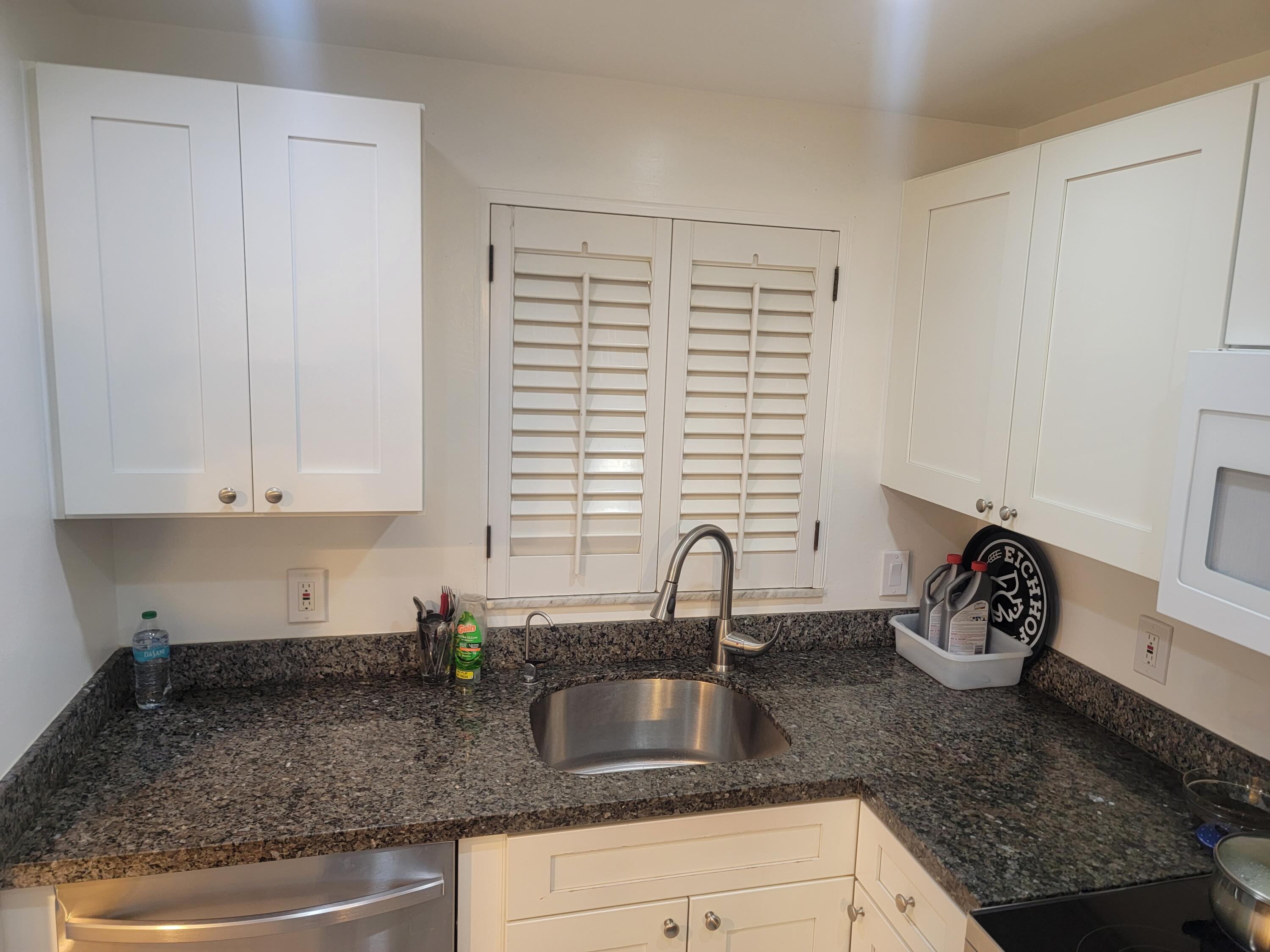 a kitchen with granite countertop a sink a stove and cabinets