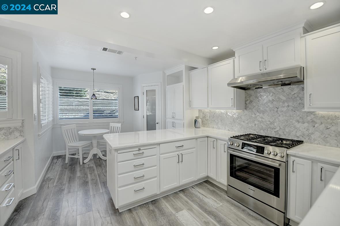 a kitchen with a stove a sink and wooden floor