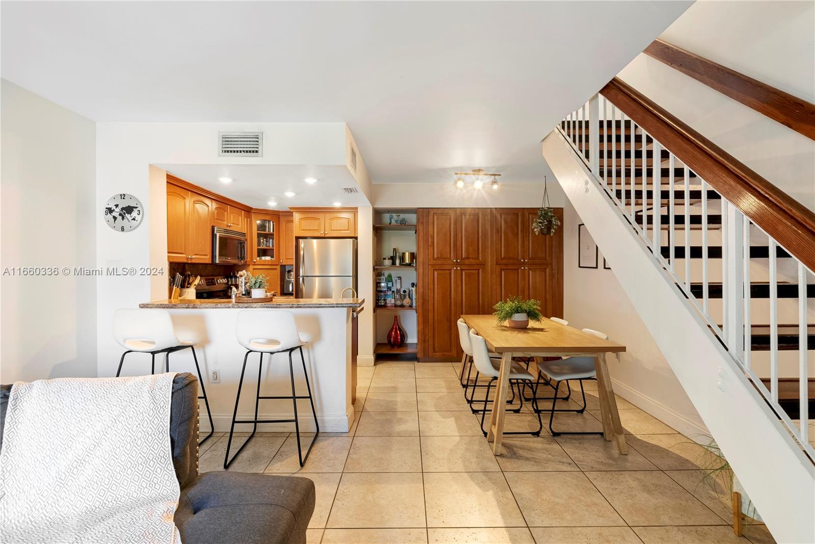 a kitchen with stainless steel appliances kitchen island granite countertop a table chairs and a refrigerator