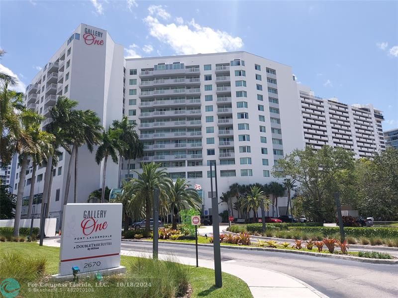 a front view of multi story residential apartment building with yard and sign board