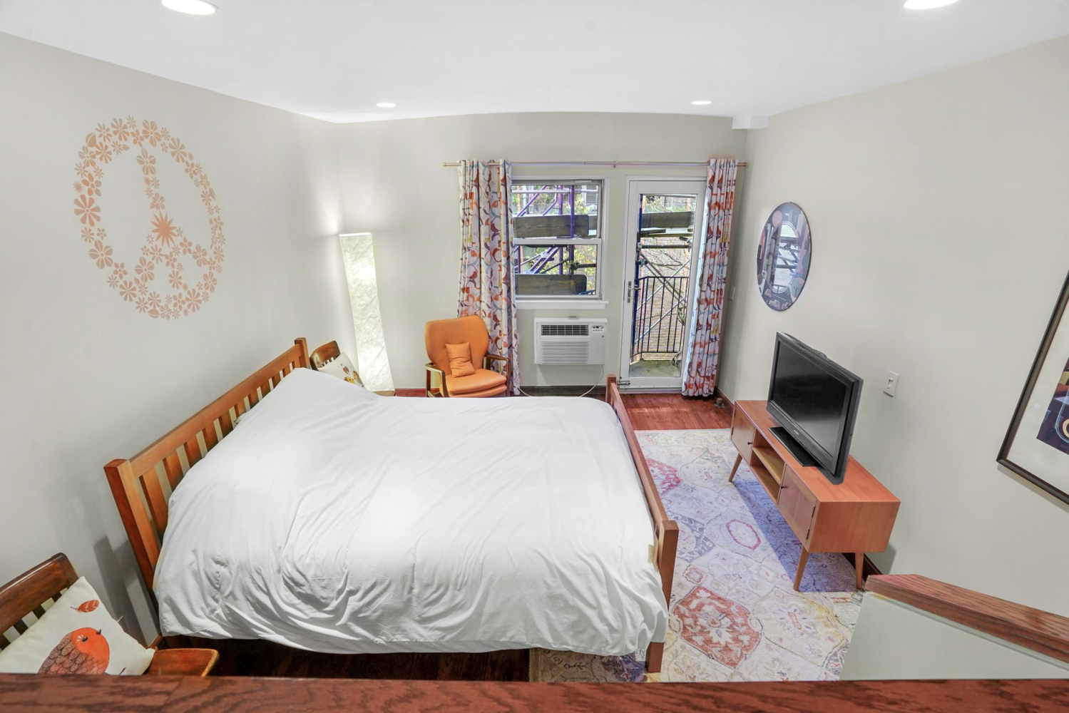 a bedroom with a bed and dresser with wooden floor