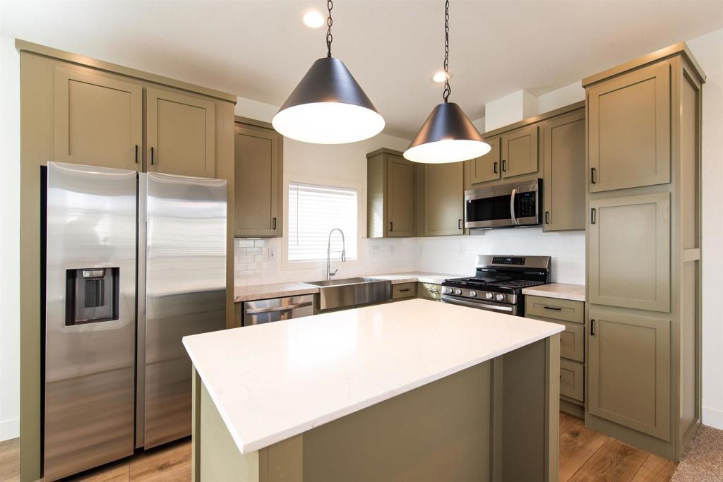 a kitchen with a refrigerator a sink a center island and cabinets