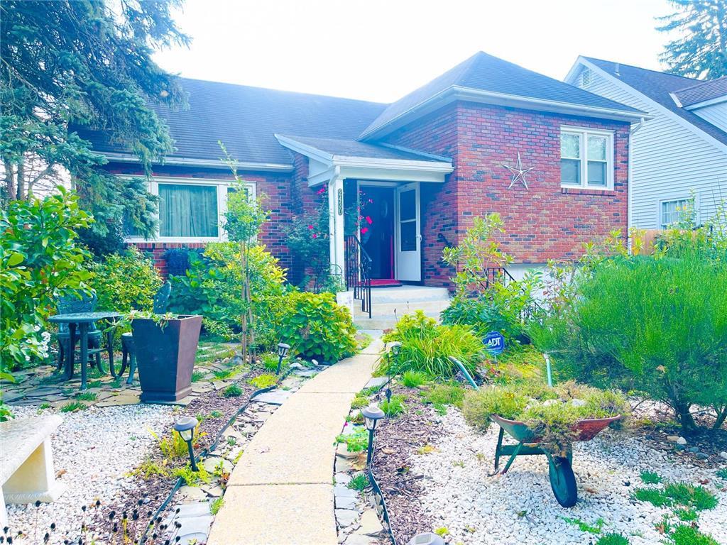 a view of a brick house with a yard and plants