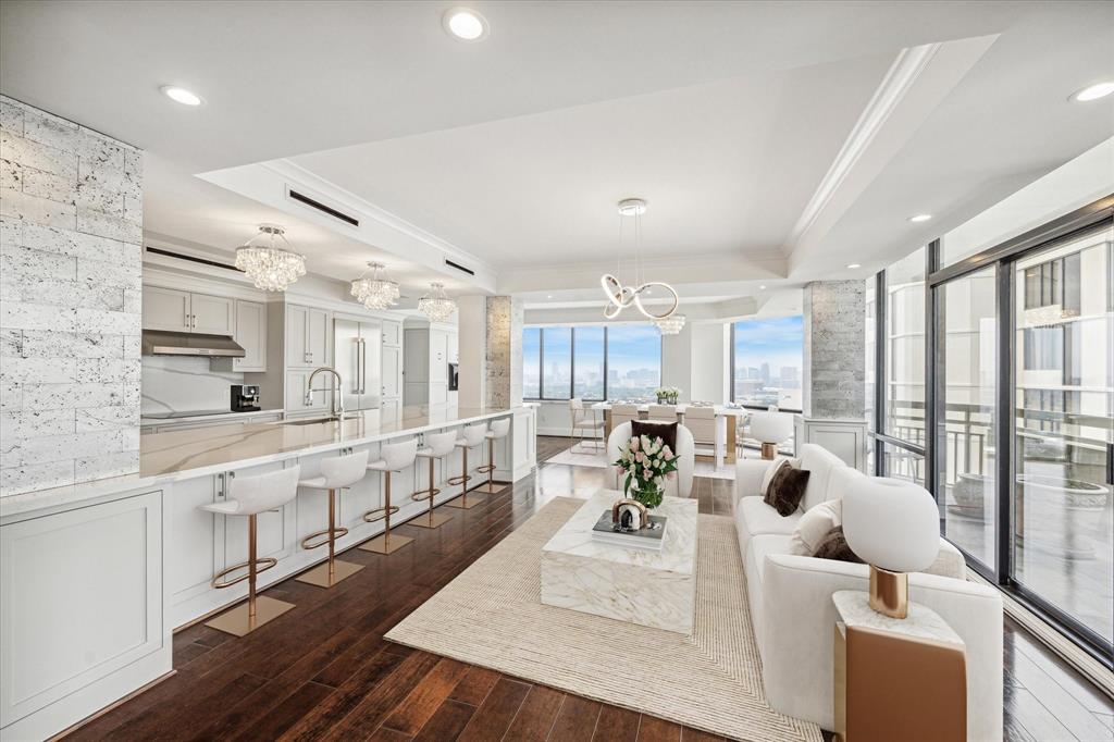 a large room with lots of white furniture wooden floor and a large window