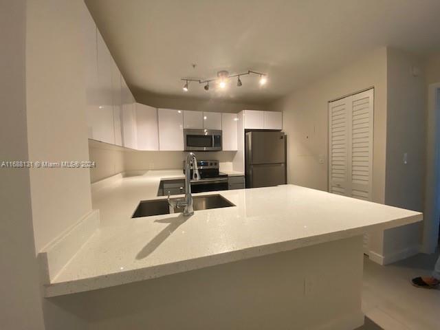 a large white kitchen with kitchen island a sink stainless steel appliances and cabinets