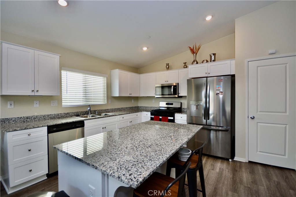 a kitchen with granite countertop kitchen island cabinets stainless steel appliances and a counter space