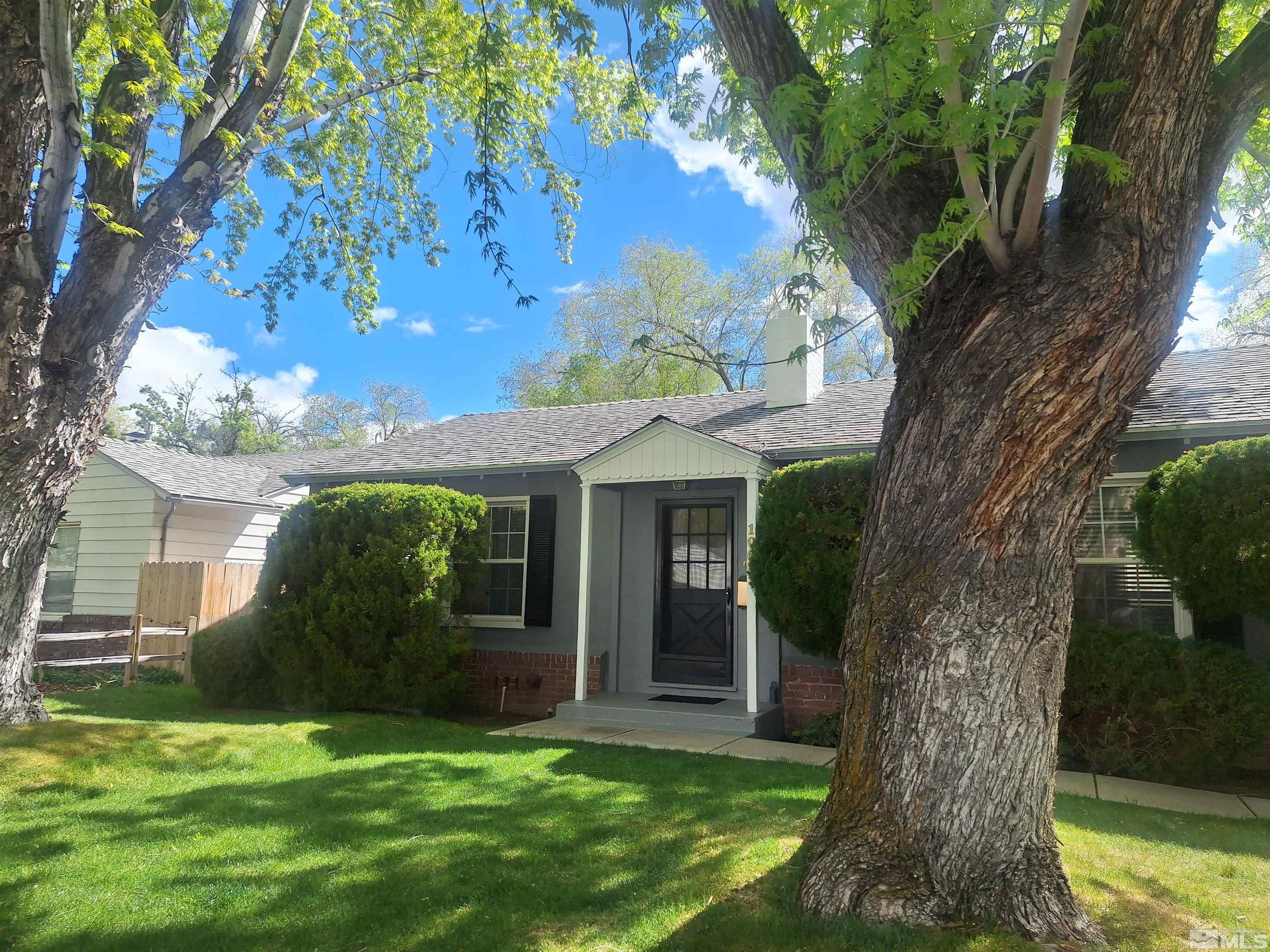 a view of a white house next to a yard with a tree