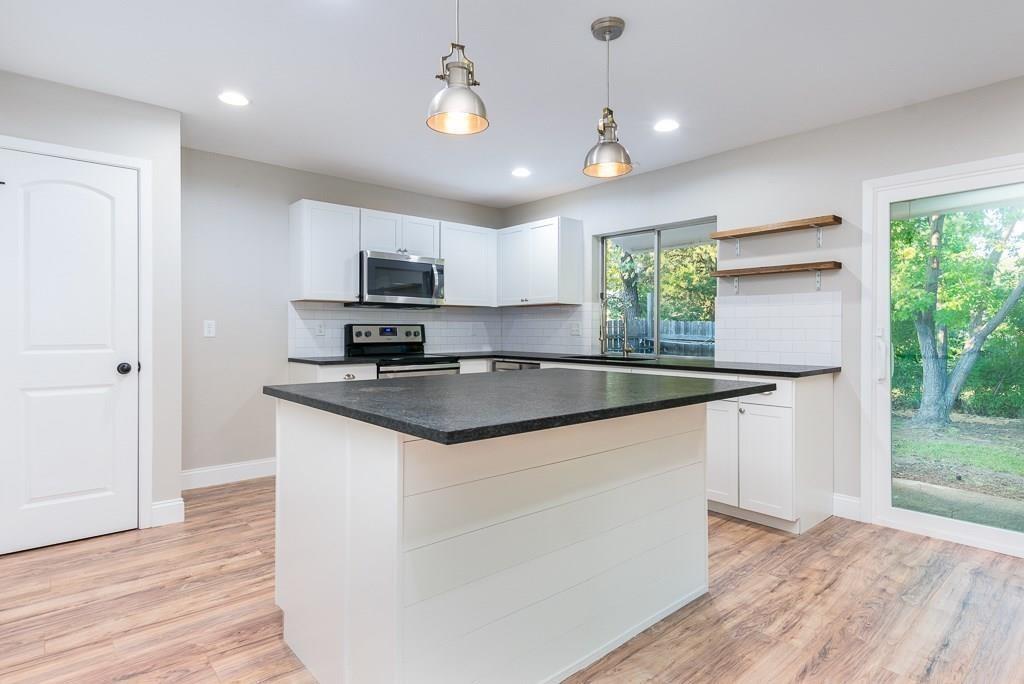 a kitchen with granite countertop a stove a sink and a refrigerator