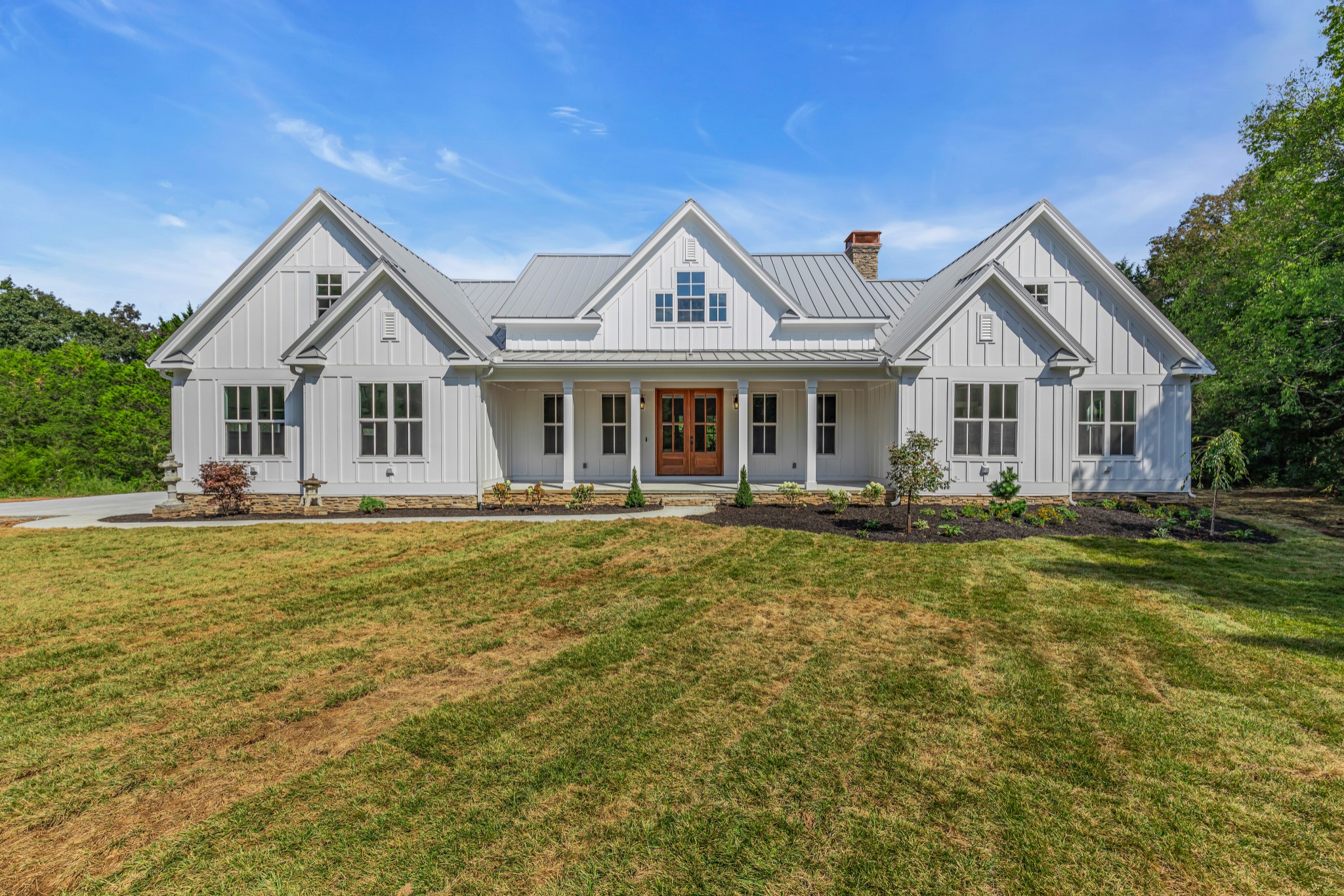 a front view of a house with a garden and lake view