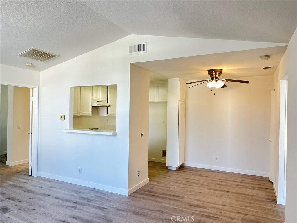 an empty room with wooden floor and a ceiling fan