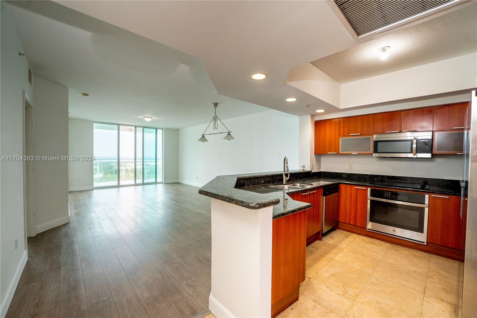 a kitchen with stainless steel appliances granite countertop a sink a stove and a wooden floors