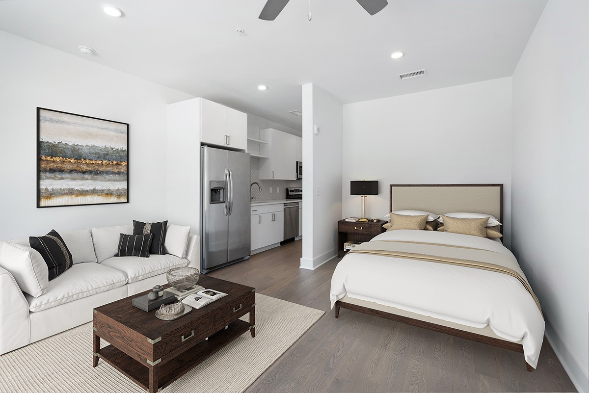 a bedroom with a bed couch and kitchen view