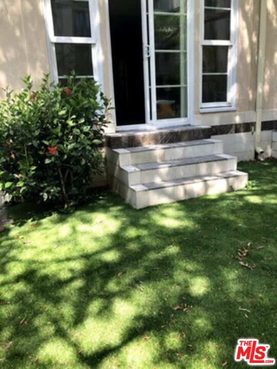 a view of a backyard with potted plants and large trees