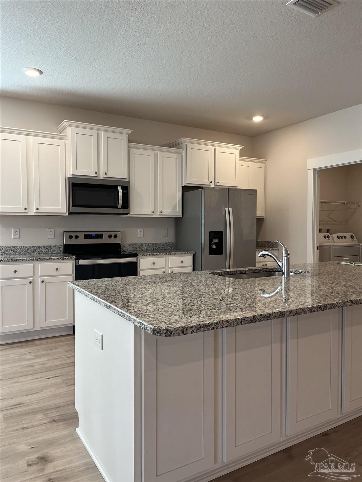 a kitchen with granite countertop white cabinets and a stainless steel appliances