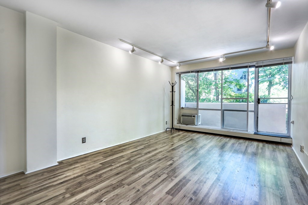 a view of an empty room with wooden floor and a window