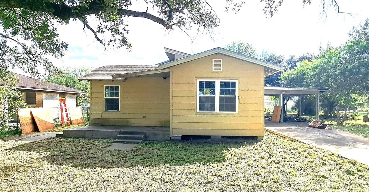 a view of a house with a yard chairs and wooden fence