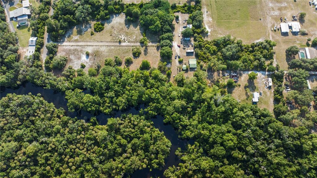 an aerial view of residential house with outdoor space and trees all around