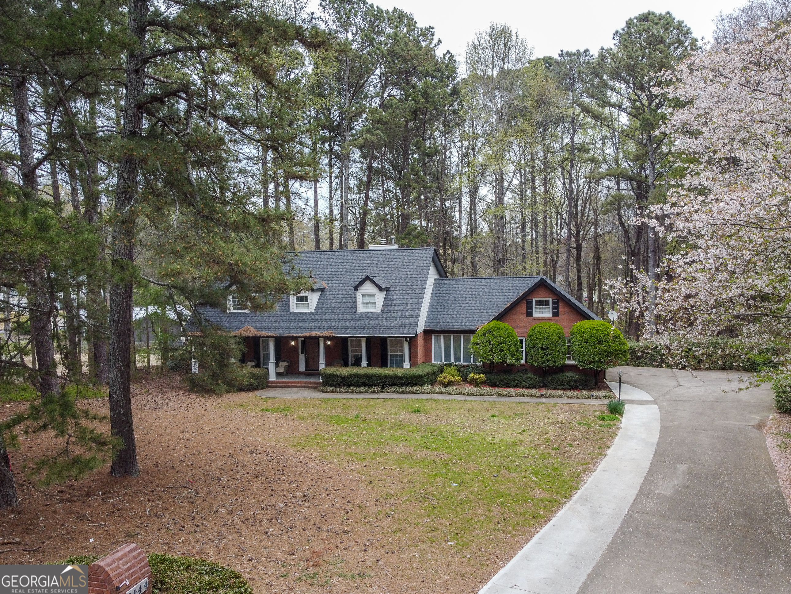 a front view of a house with a yard and large trees