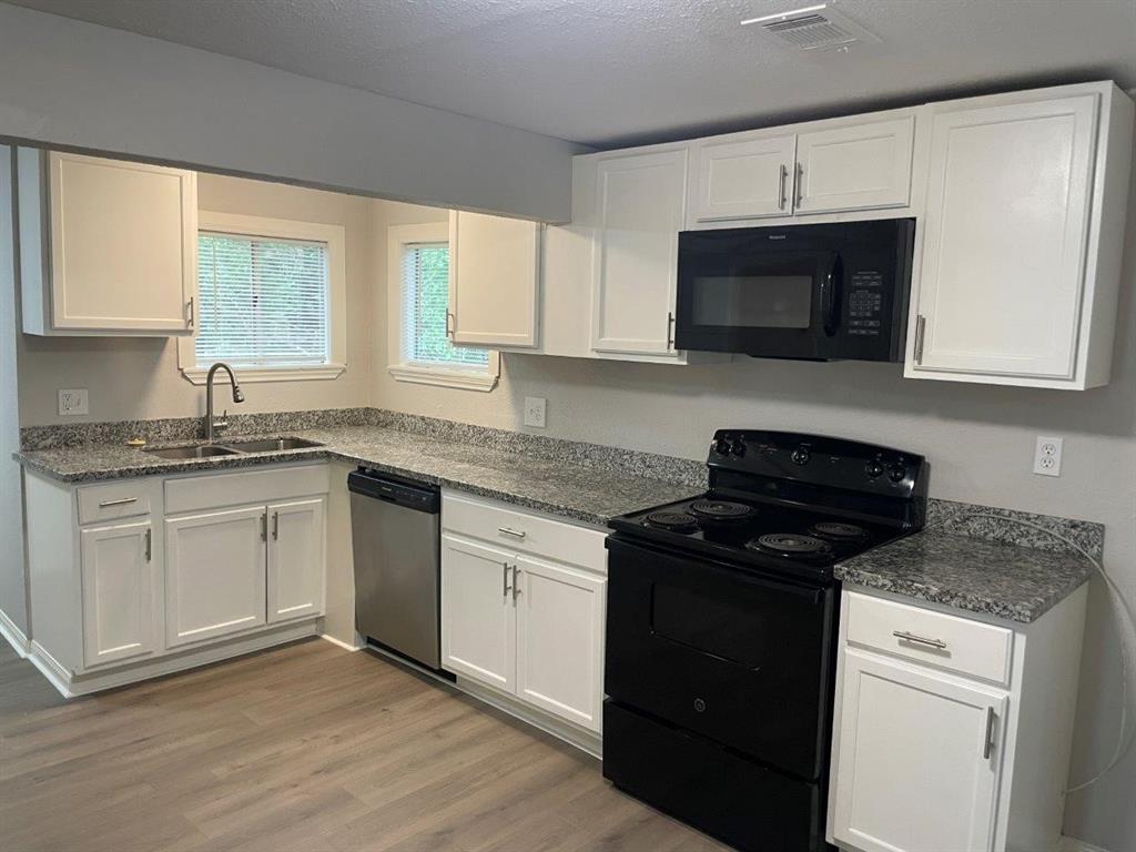 a kitchen with granite countertop white cabinets and black appliances