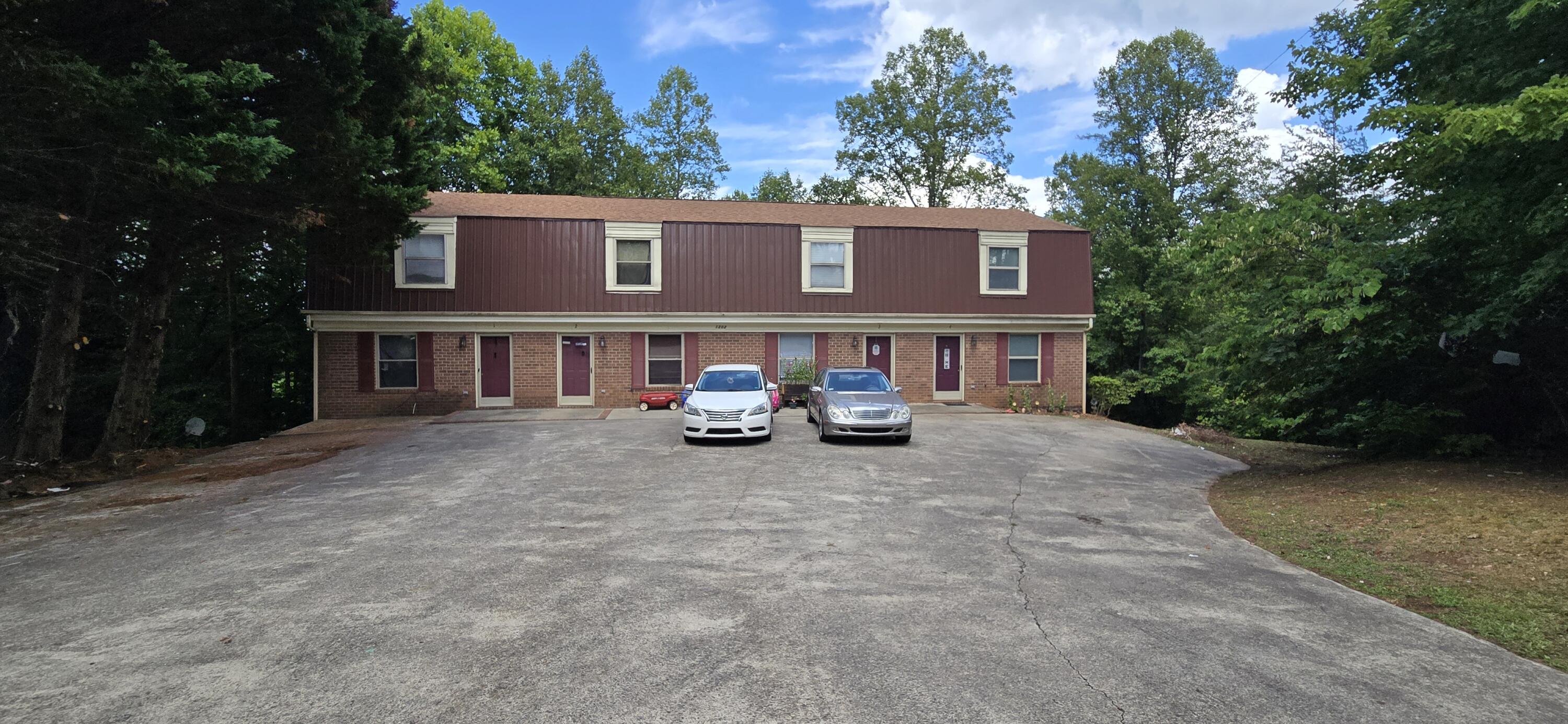 a view of a blue house with a yard and parking space