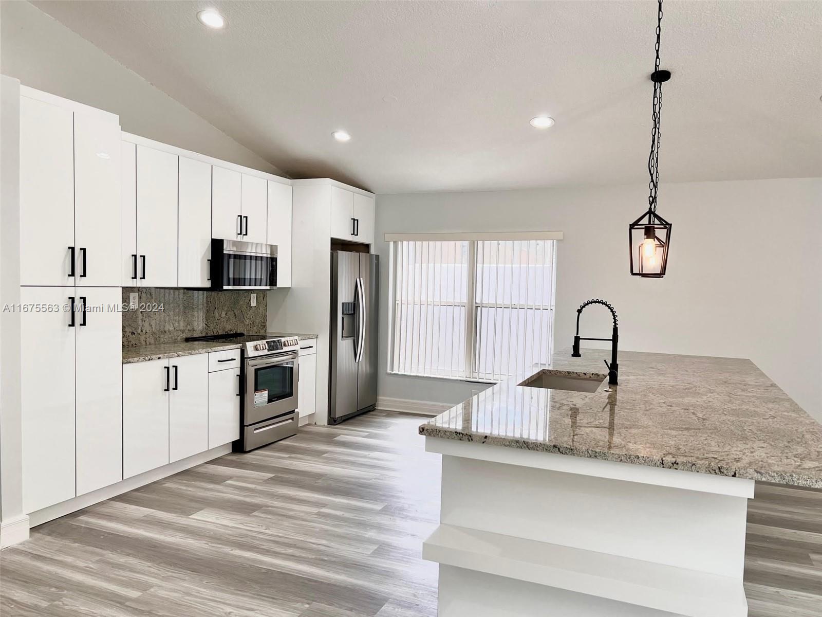 a kitchen with kitchen island granite countertop a sink stainless steel appliances and cabinets