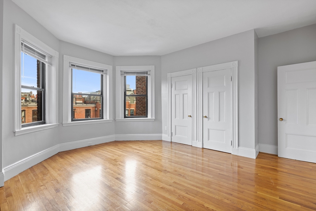 a view of an empty room with glass door and wooden floor