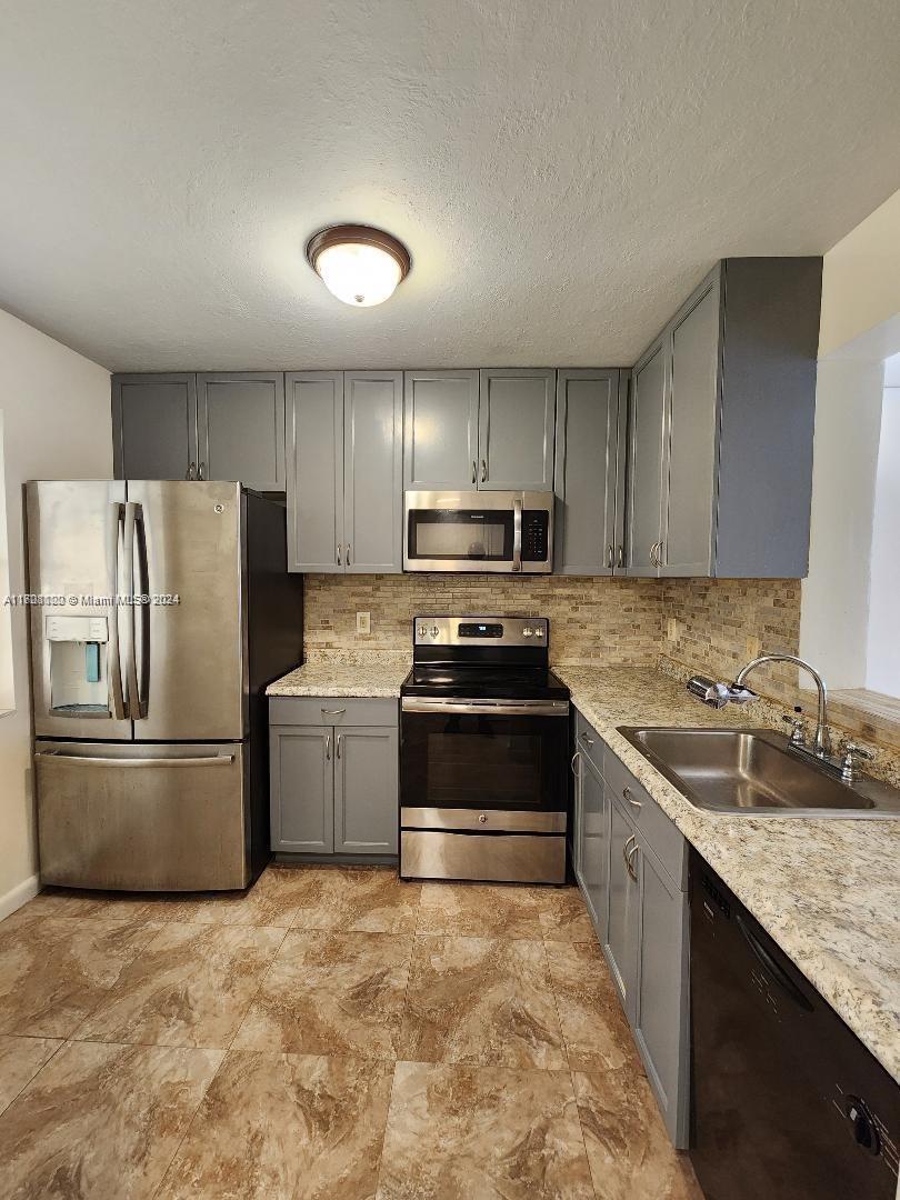 a kitchen with granite countertop a refrigerator and a stove top oven