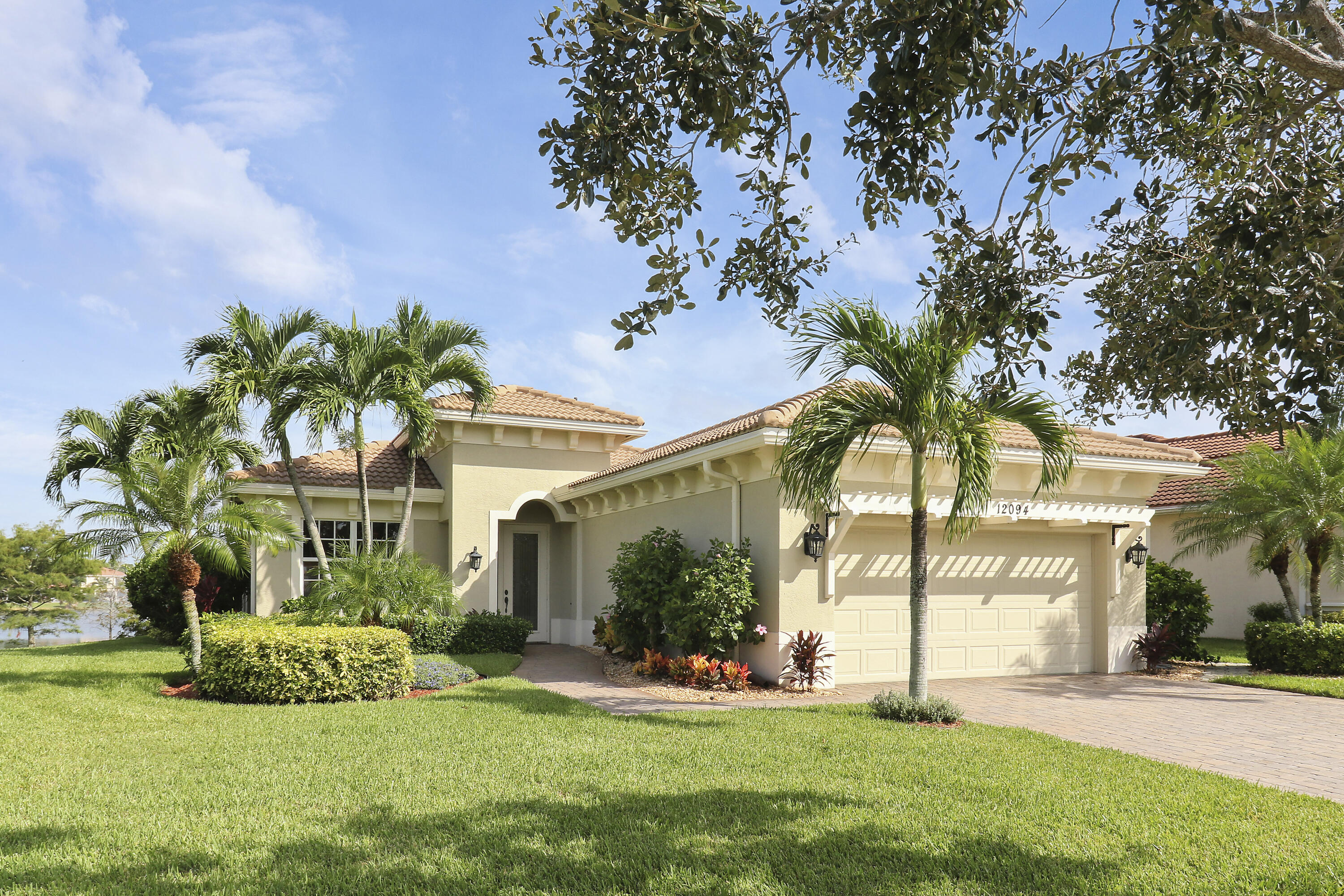 a view of a white house with a big yard and potted plants and a large tree