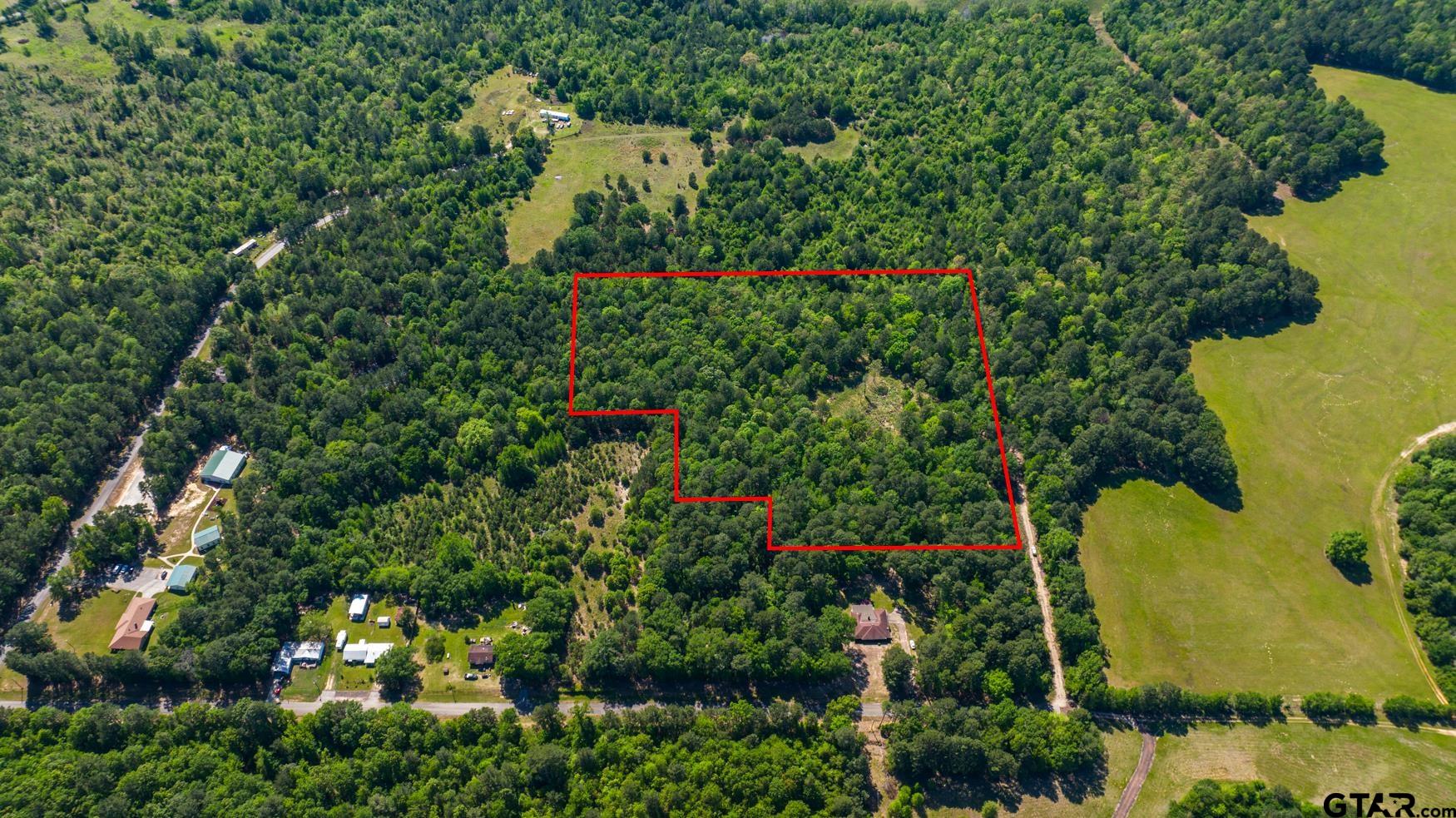 an aerial view of residential house with outdoor space and trees all around