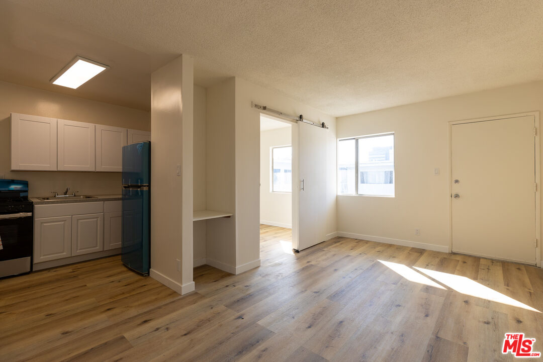 a view of empty room with wooden floor and electronic appliances