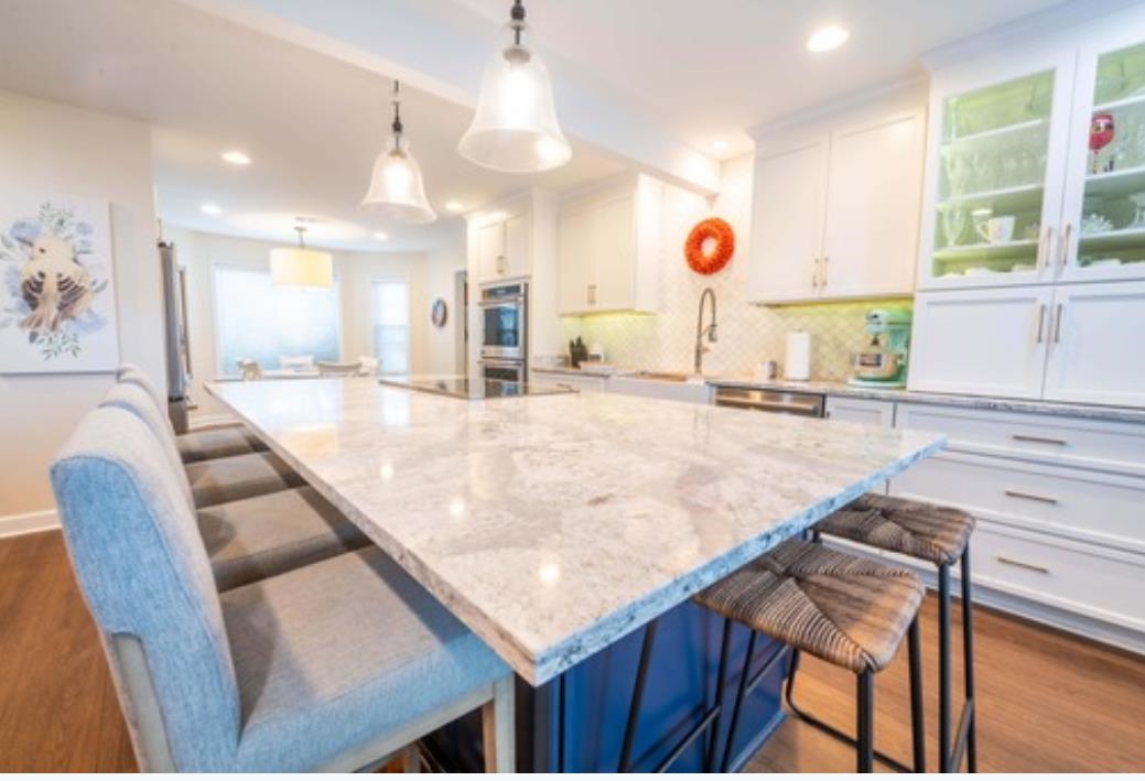 Kitchen featuring a large island, dark hardwood / wood-style floors, a kitchen breakfast bar, and white cabinetry