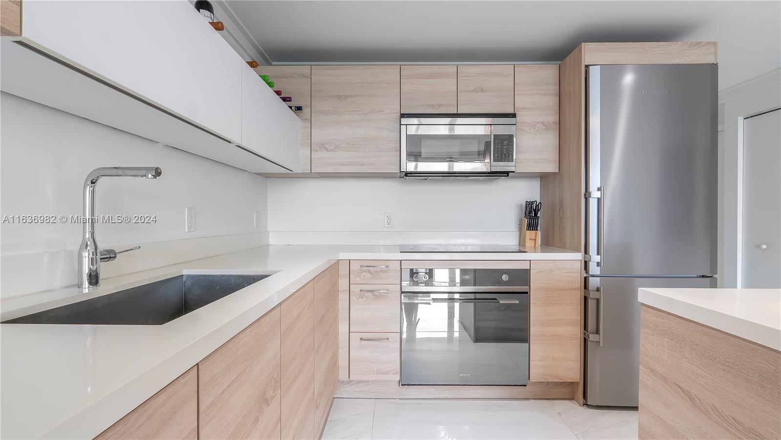 a kitchen with stainless steel appliances granite countertop a sink and a refrigerator