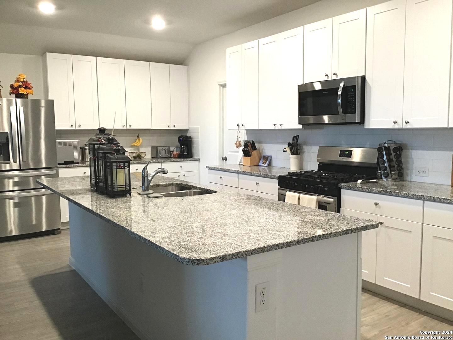 a kitchen with stainless steel appliances granite countertop a sink a stove and cabinets