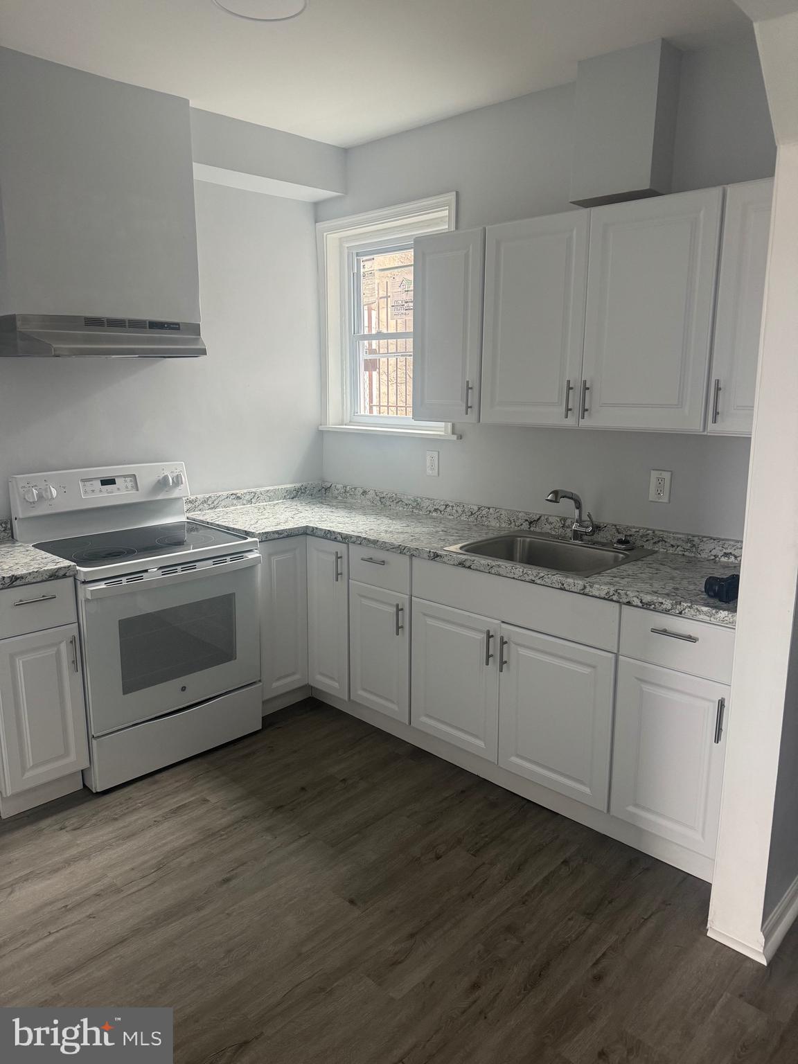 a kitchen with stainless steel appliances granite countertop a stove a sink and white cabinets