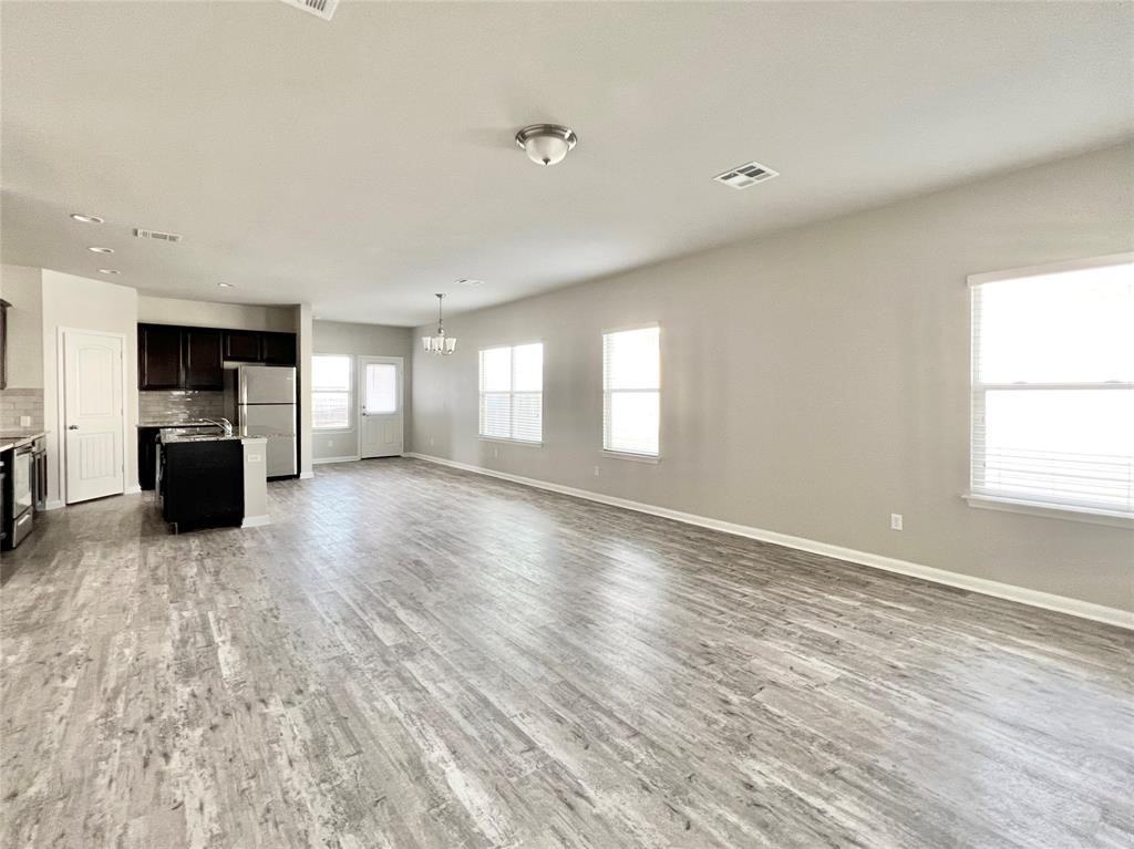 a view of empty room with wooden floor and windows