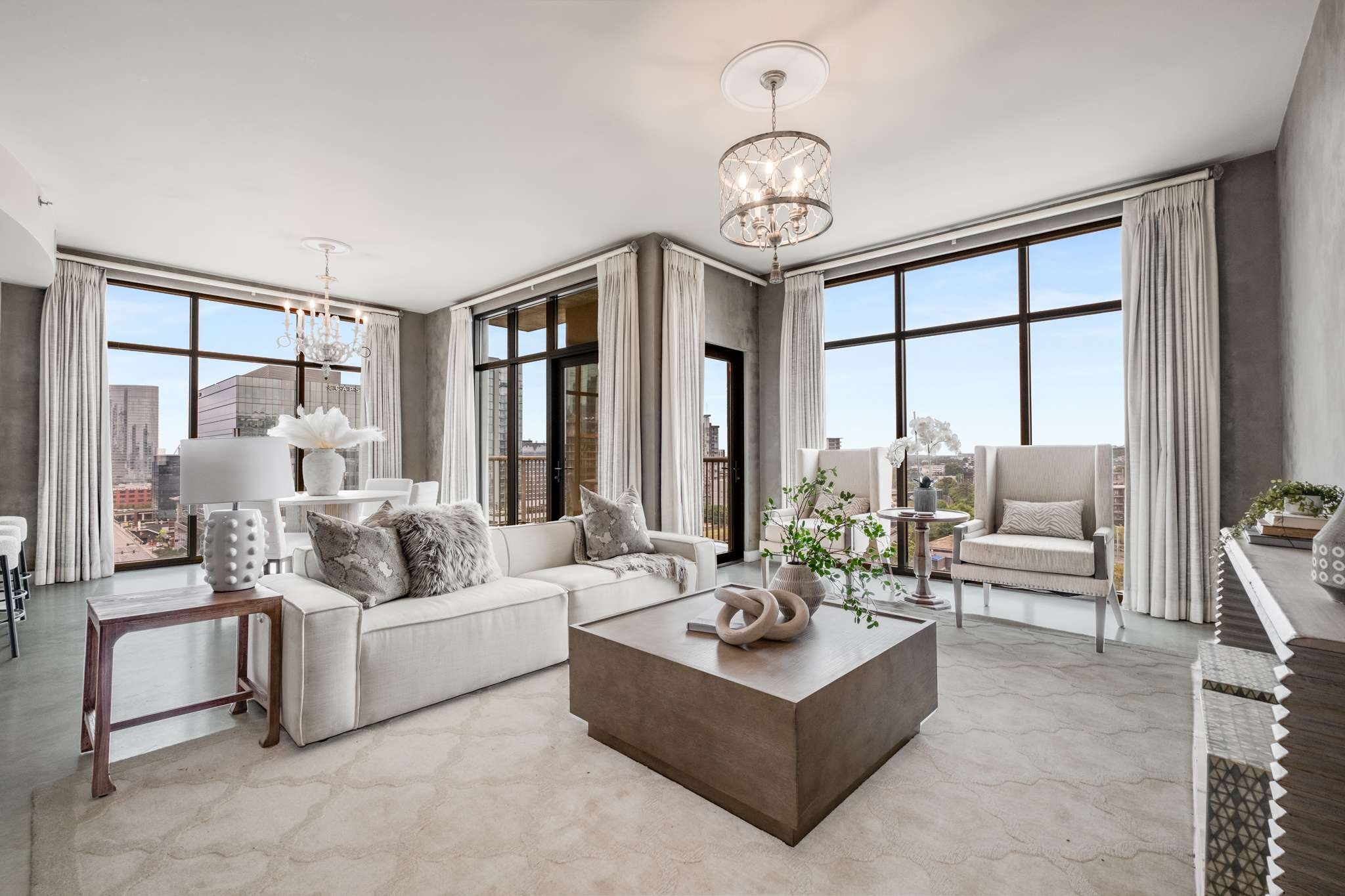 a living room with furniture large windows and a chandelier